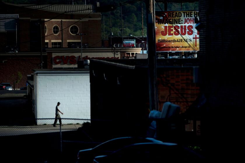 A man walks down an ally near a billboard for Jesus on April 20, 2017 in Huntington, West Virginia. - Huntington, the city in the northwest corner of West Virginia, bordering Kentucky, has been portrayed as the epicenter of the opioid crisis. On August 15, 2016, from 3:00 pm to 9:00 pm, 28 people in the city overdosed on heroin laced with fentanyl, a synthetic opioid far more powerful and dangerous than heroin. The economic incentives are powerful: one kilogram of fentanyl costs $5,000, which can make a million tablets sold at $20 each for a gain of $20 million. "This epidemic doesn't discriminate," Huntington Mayor Steve Williams said. "Our youngest overdose was 12 years old. The oldest was 77." (Photo by Brendan Smialowski / AFP) / TO GO WITH AFP STORY by Heather SCOTT, US-health-drugs-WestVirginia (Photo credit should read BRENDAN SMIALOWSKI/AFP via Getty Images)