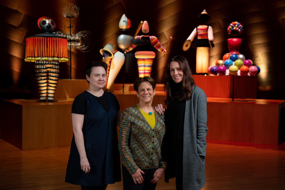 Los Angeles Philharmonic humanities director Julia Ward, left, stands with curators Stephanie Barron and Nana Bahlmann in front of designs from Oskar Schlemmer’s Triadic Ballet, on display at Walt Disney Concert Hall.
