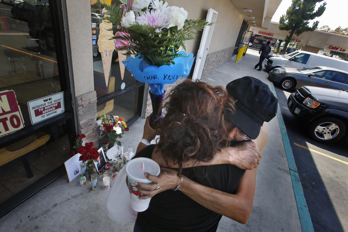 Two mourners embrace outside a Santa Ana shop where a police officer shot and killed a homeless man who frequently spent time in Costa Mesa.