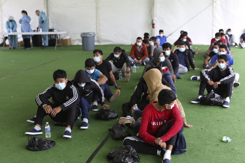 Young migrants sit in a line on the floor at the Donna Department of Homeland Security holding facility