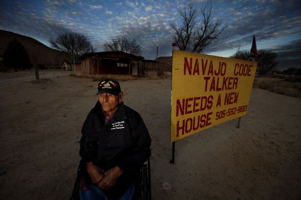 World War II veteran Tom Jones, Jr., an 89-year-old Navajo Code Talker, sits next to a sign on his dwelling asking for help.