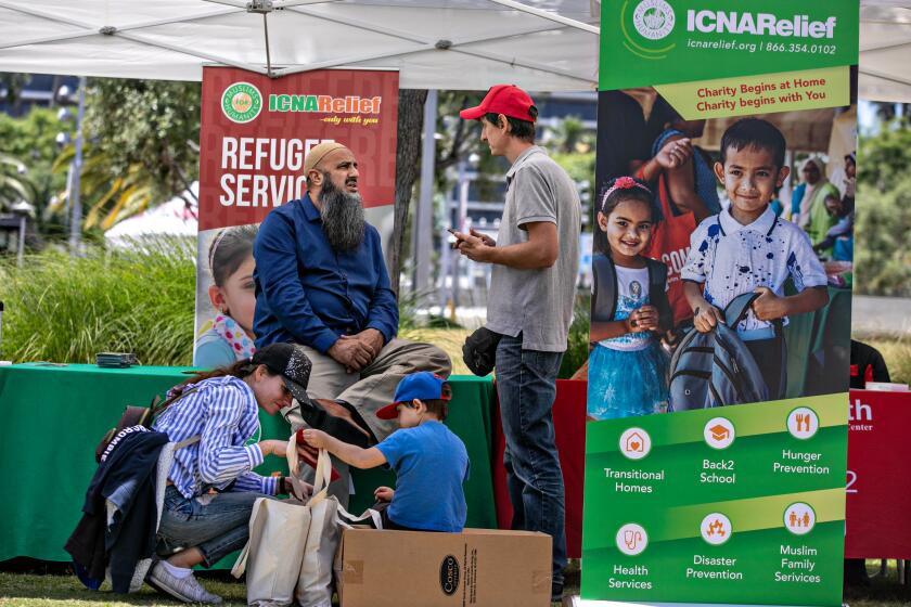 Los Angeles, CA - June 20: Vladyslav Kohut's along with his wife Oleksandra and their son Maksym, 4, receive support migrant services fro Abdullah Zikria (center), OC, LA & Central CA Outreach Coordinator for ICNA Relief at the World Refugee Day at Gloria Molina Grand Park in downtown Los Angeles on Tuesday, June 20, 2023 in Los Angeles, CA. The Kohut's are Ukrainian refugees who just arrived in Los Angeles from Texas three days ago. (Jason Armond / Los Angeles Times)