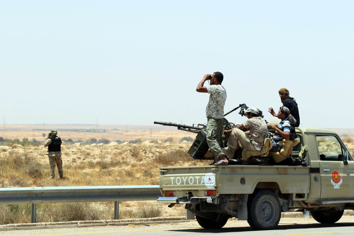 Forces loyal to Libya's U.N.-backed unity government sit on the back of an armored vehicle at the entrance to Surt as they advance to recapture the city from the Islamic State group jihadists on June 10.