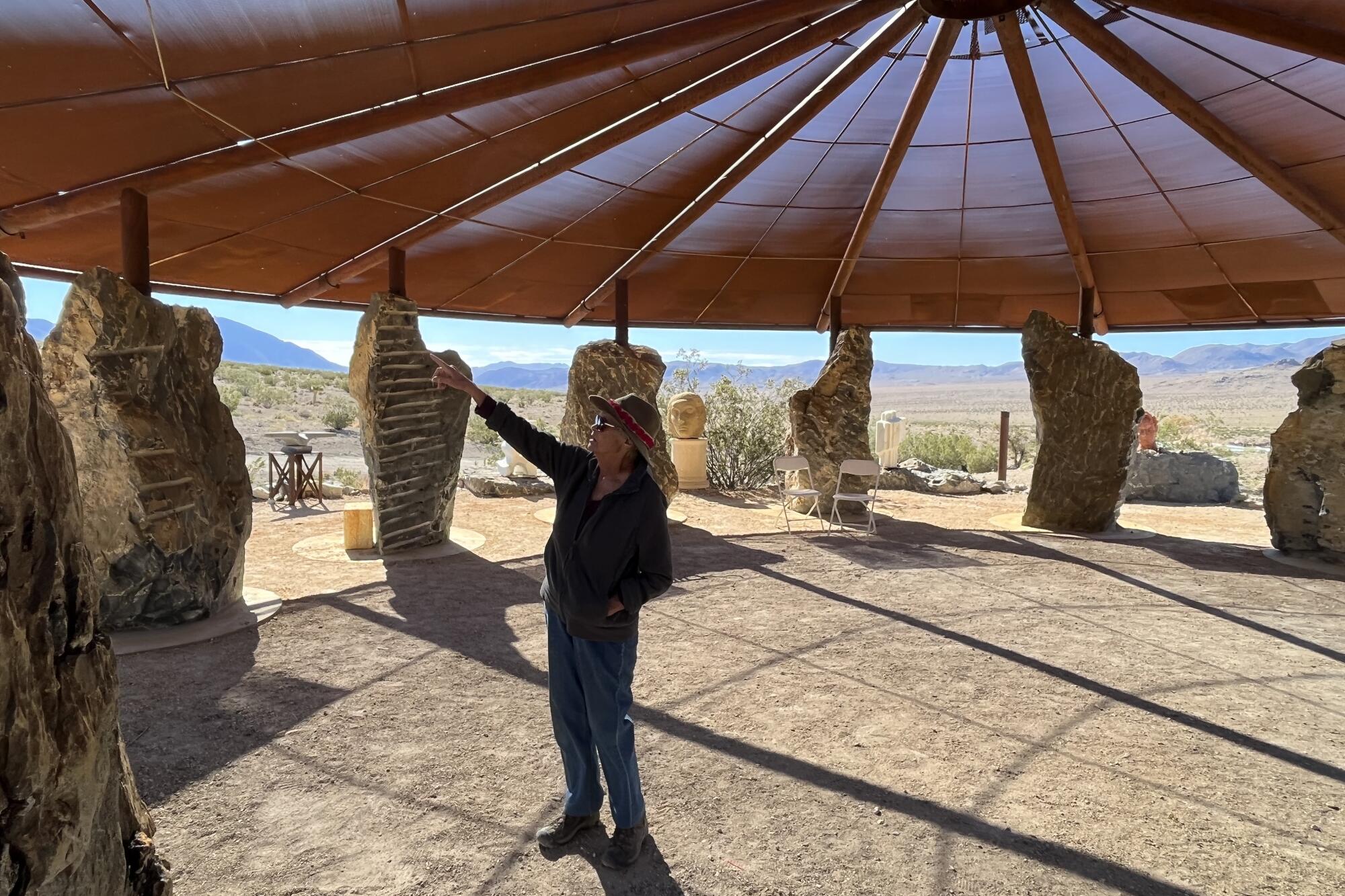 A woman stands under a steel canopy supported by 12 black dolomite boulders.