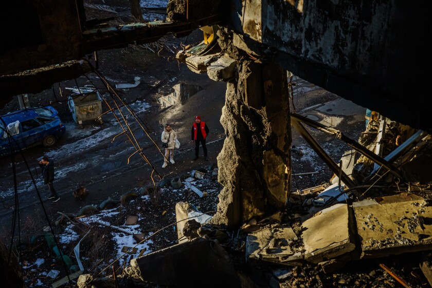 Two people look up at a destroyed apartment building in Kharkiv.