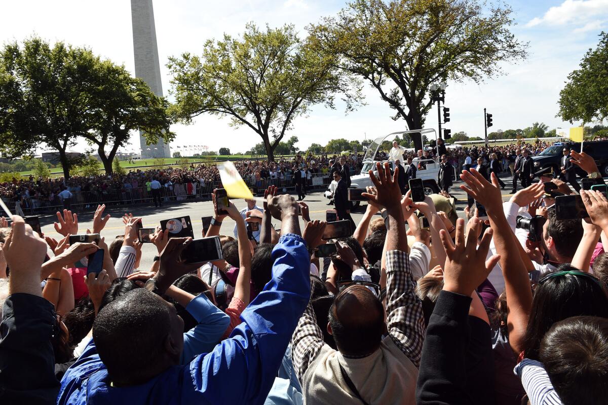Spectators wave to Pope Francis during a parade on the streets around the White House in Washington, DC.