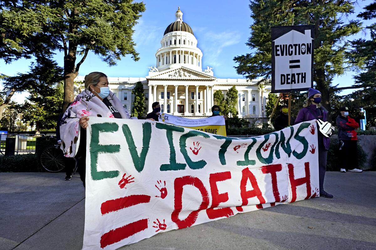 Demonstrators hold signs against evictions in front of the Capitol in Sacramento