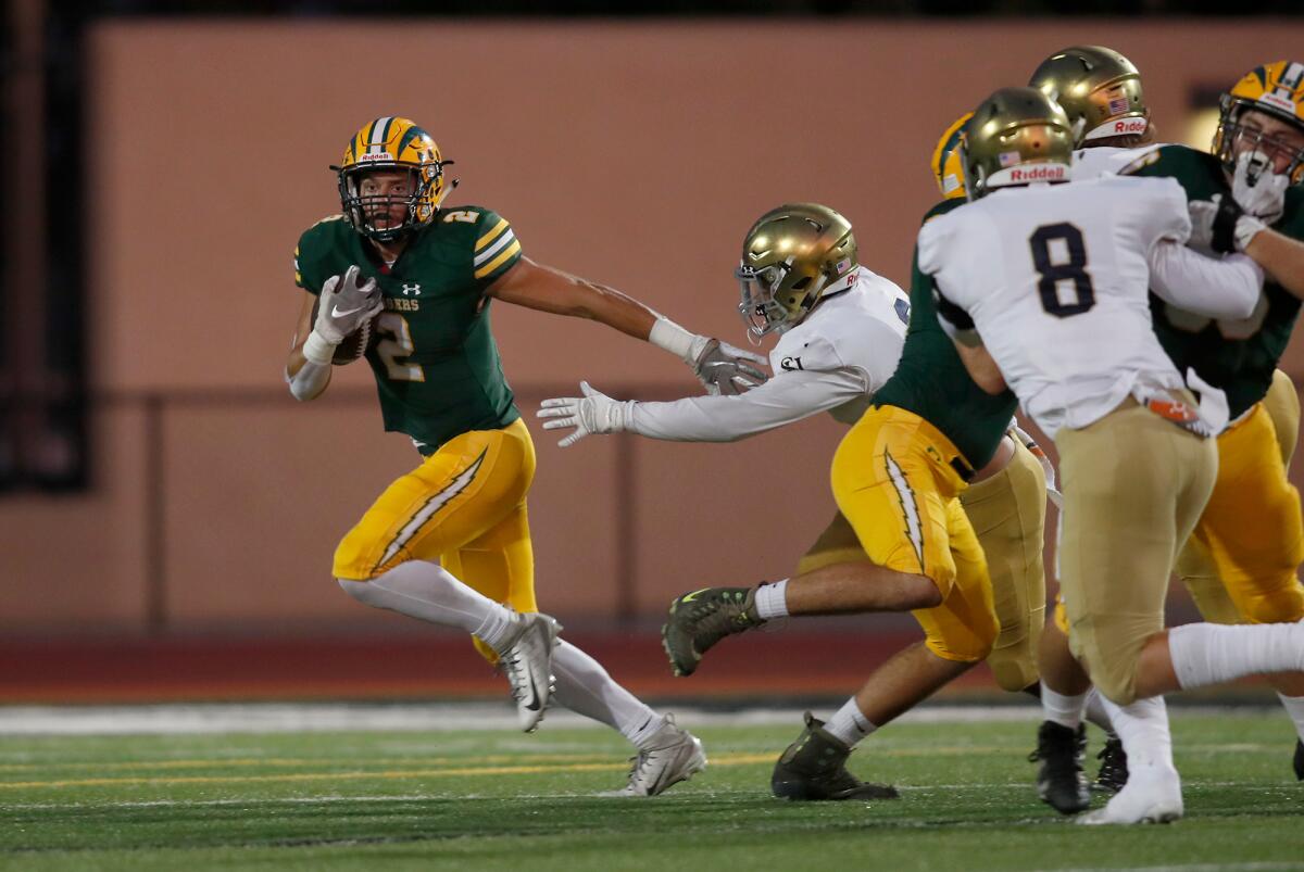 Mike Walters, left, carries the ball for Edison against San Juan Hills during the first half of a nonleague home game at Huntington Beach High on Friday.
