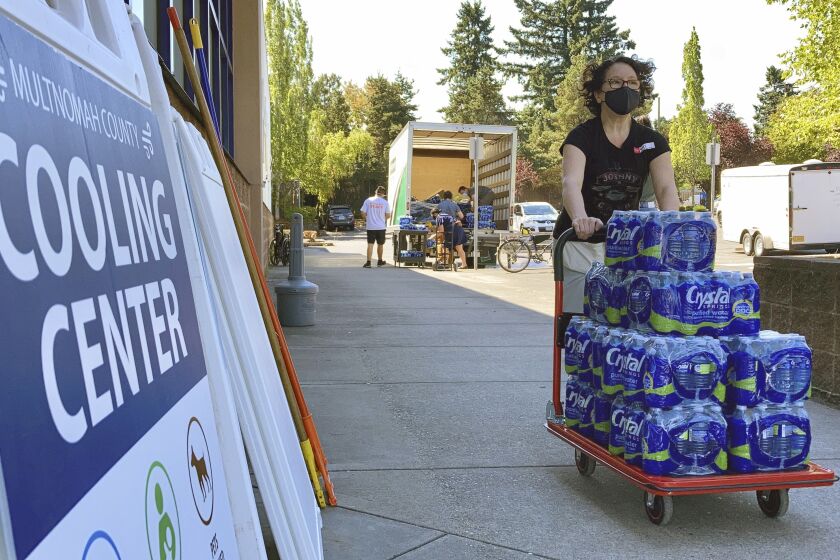 FILE - A volunteer unloads bottled water at a cooling center established to help vulnerable residents ride out a dangerous heat wave on Aug. 11, 2021. Oregon is set to become the first state in the nation to cover certain climate change expenses under its Medicaid program. State health officials say the low-income health plan will cover devices such as air conditioners, air filters and generators (AP Photo/Gillian Flaccus, File)