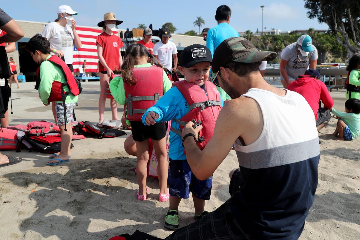 Davian Castrillon, 3, of Fullerton gets his life vest fastened by his father David as they participate on Thursday.