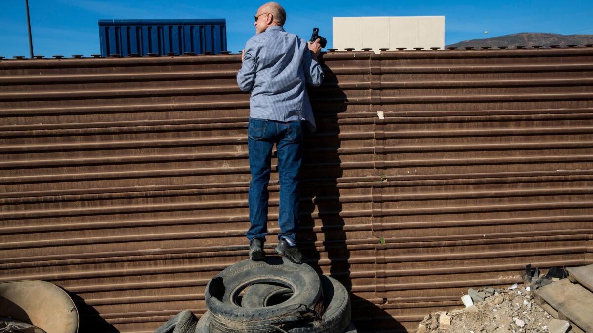 From the Tijuana side, John Thurston peers over the border fence to view border wall prototypes.