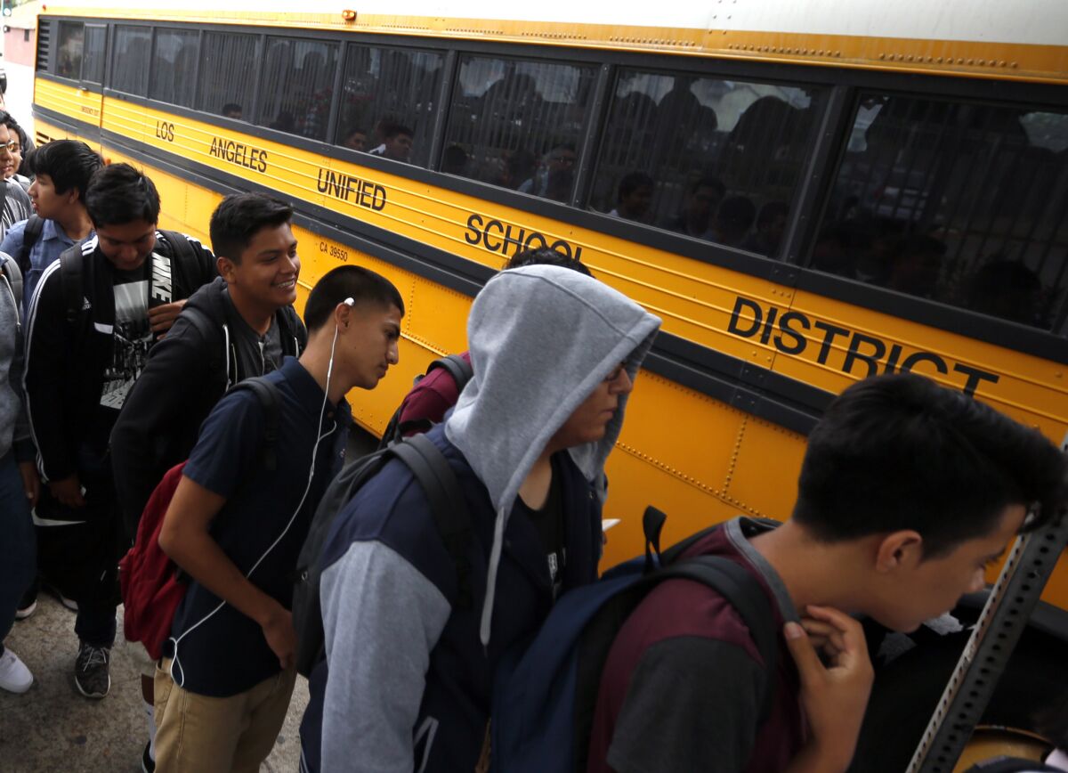 Students line up for their buses at a district stop near Jefferson High School in Los Angeles on the first day of classes in 2015. In California, 58% of Latinos attend “intensely segregated schools,” a recent report says.