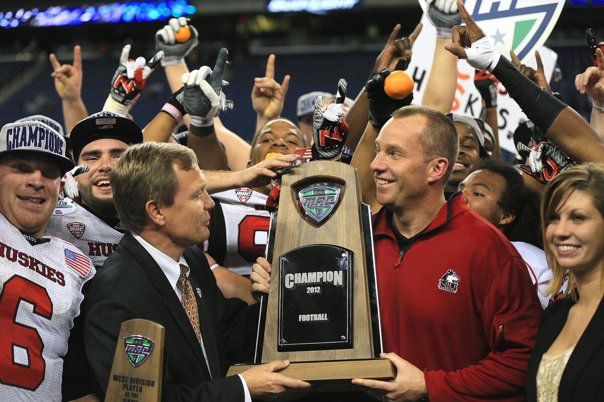 Coach Dave Doeren is presented the championship trophy by MAC Commissioner Dr. Jon A. Steinbrecher after Northern Illinois defeated Kent State on Saturday.