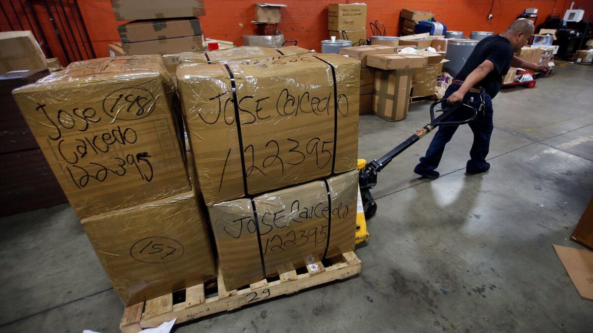 Victor Alavez, a packer at Olarte Transport, moves boxes containing donated necessities to be shipped to Jose Caicedo in Caracas, Venezuela.