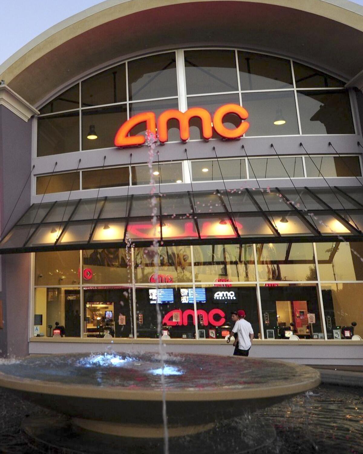 The exterior of an AMC Theatre with a glass front and a water fountain feature in the foreground