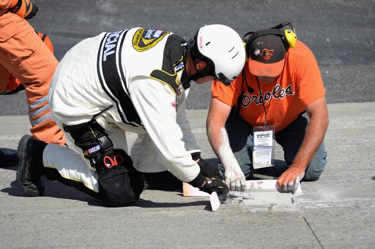 Track workers patch a hole in Dover International Speedway track during the NASCAR Sprint Cup Series race on Sunday.
