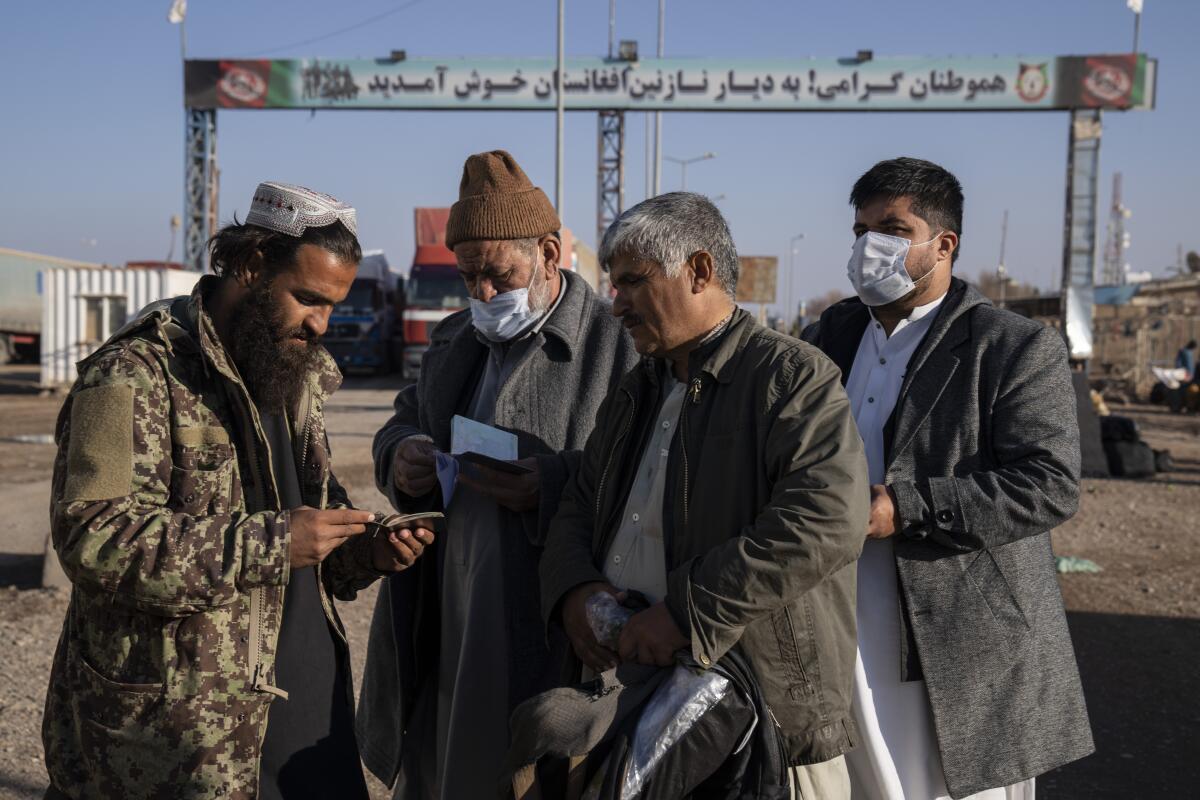 A Taliban fighter checks the passports of three men at the Afghanistan-Iran border.