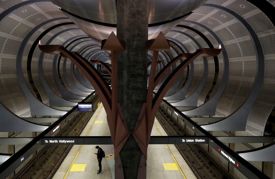 A man with a mask waits alone on the platform of the Metro Hollywood/Highland station in Hollywood.