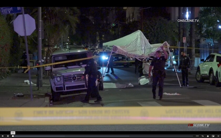 An image from video shows police behind crime tape on a street.