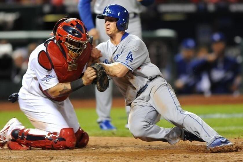 Cardinals catcher Yadier Molina braces for the collision, and appears to fail to apply the tag, as Dodgers second baseman Mark Ellis tries to score on a flyout by Michael Young in the 10th inning of Game 1.