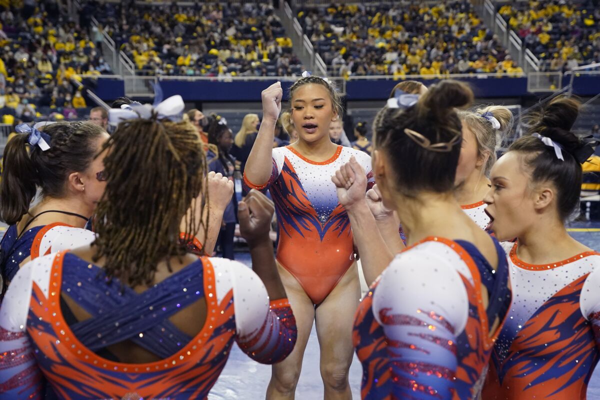 Auburn gymnast Sunisa Lee gathers with teammates before performing at a meet at the University of Michigan, Saturday, March 12, 2022, in Ann Arbor, Mich. A record crowd came out to watch Lee, the reigning Olympic champion, and Auburn take on defending national champion Michigan. The arrival of Lee and several of her Olympic teammates at the collegiate level is helping fuel a spike in interest and participation in NCAA women's gymnastics. (AP Photo/Carlos Osorio)