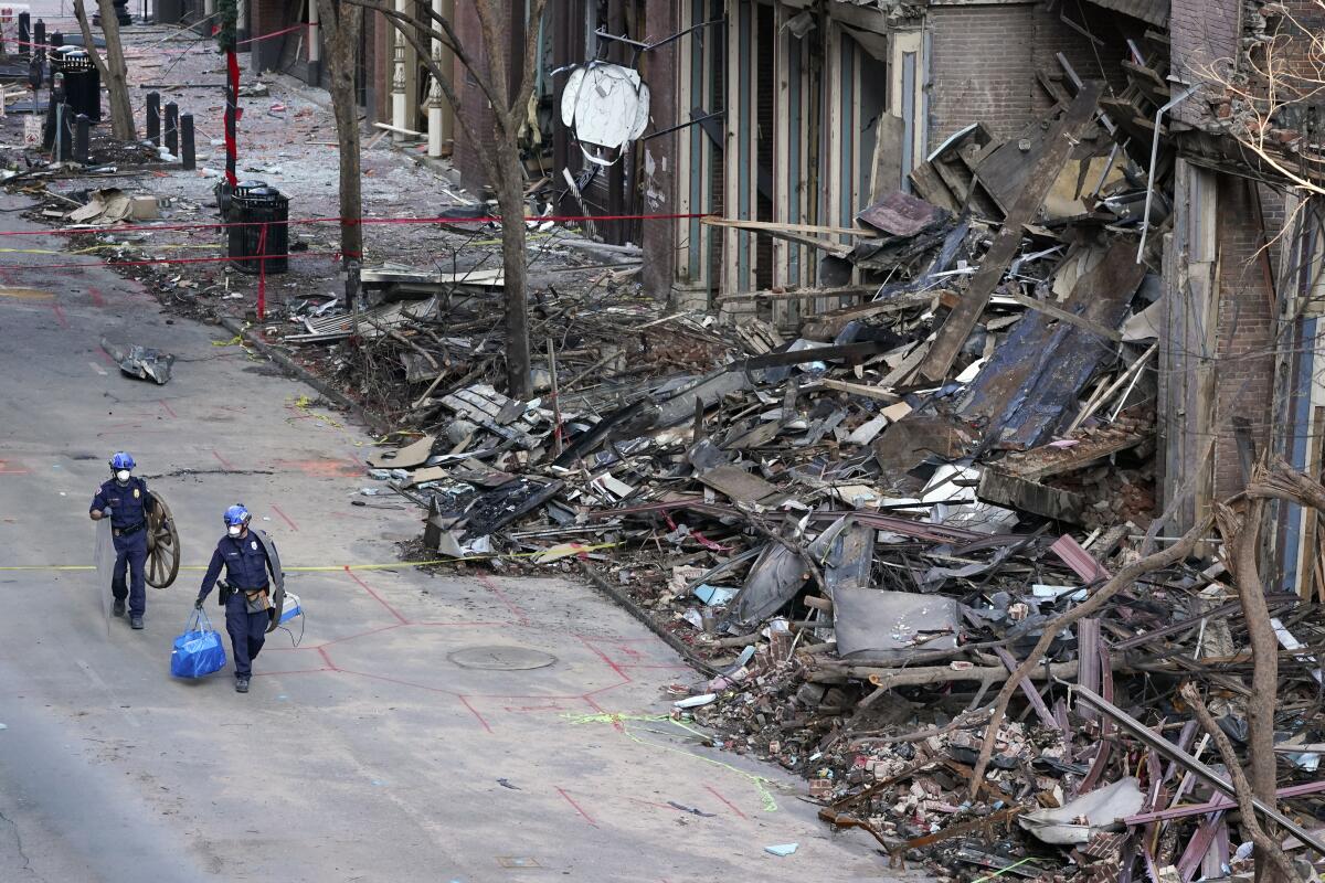 Police officers walk past buildings damaged by a bombing in Nashville.