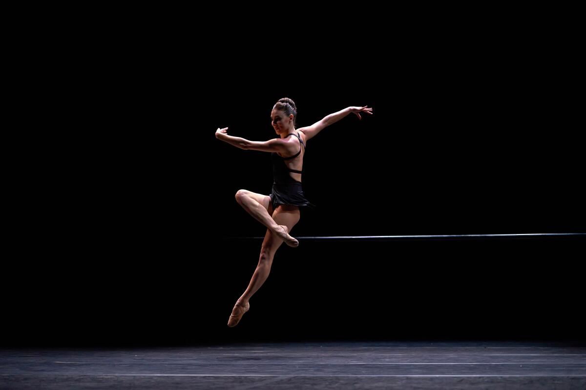 A dancer leaping forward with a leg pointed forward.