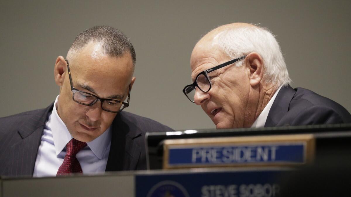 Police Commissioners Matt Johnson, left, and Steve Soboroff talk during their meeting Tuesday, when commissioners approved a new policy requiring the LAPD to release video of critical incidents involving the police.