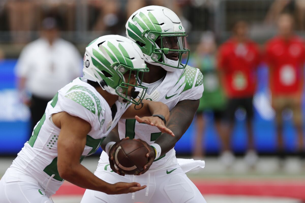 Oregon quarterback Anthony Brown, right, hands off to running back Travis Dye during the first half of an NCAA college football game Saturday, Sept. 11, 2021, in Columbus, Ohio. Oregon beat Ohio State 35-28. (AP Photo/Jay LaPrete)