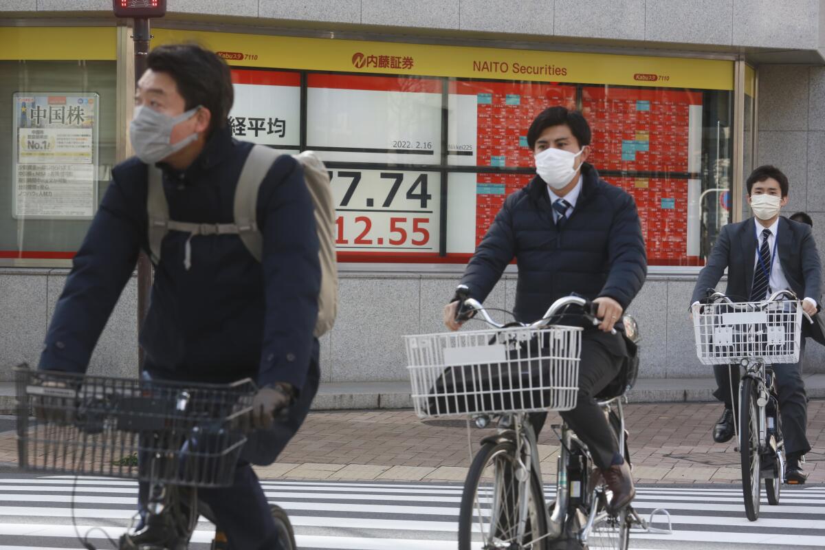 People cycle past an electronic stock board of a securities firm in Tokyo, Wednesday, Feb. 16, 2022. Asian shares rose Wednesday, buoyed by hopes for a diplomatic solution instead of a Russian invasion of Ukraine. (AP Photo/Koji Sasahara)