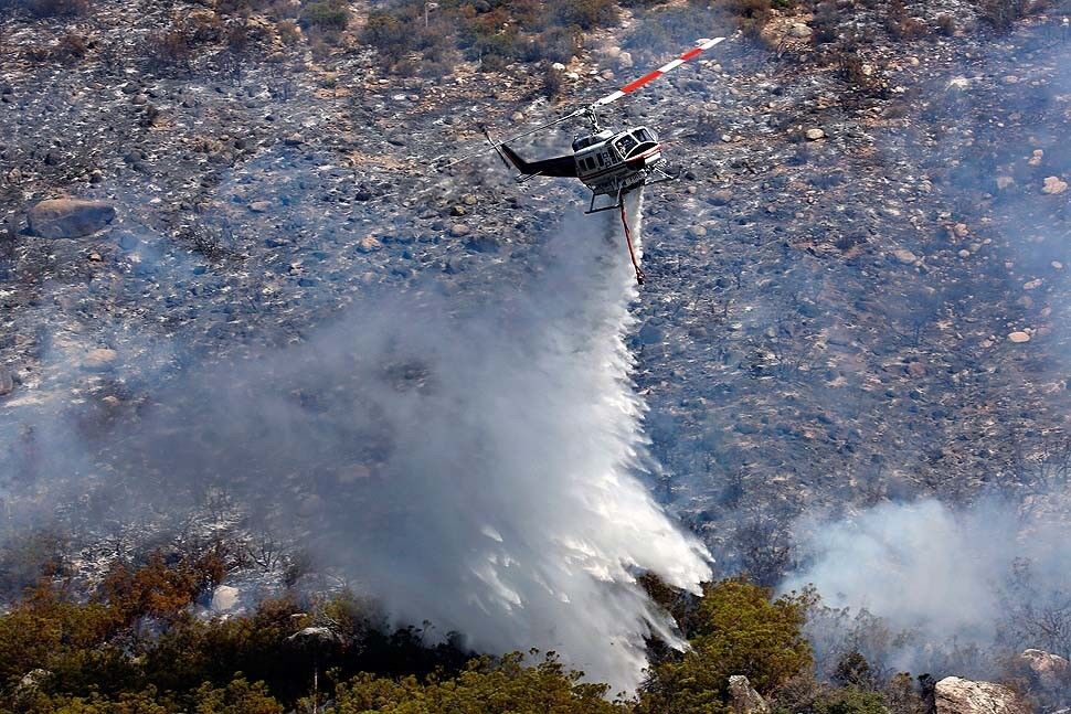 A helicopter drops water on the brush along Apple Canyon Road in Mountain Center.