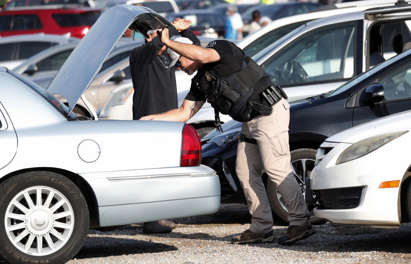 A federal agent searches the trunk of an auto leaving the employee parking lot at Koch Foods Inc. in Morton, Miss.