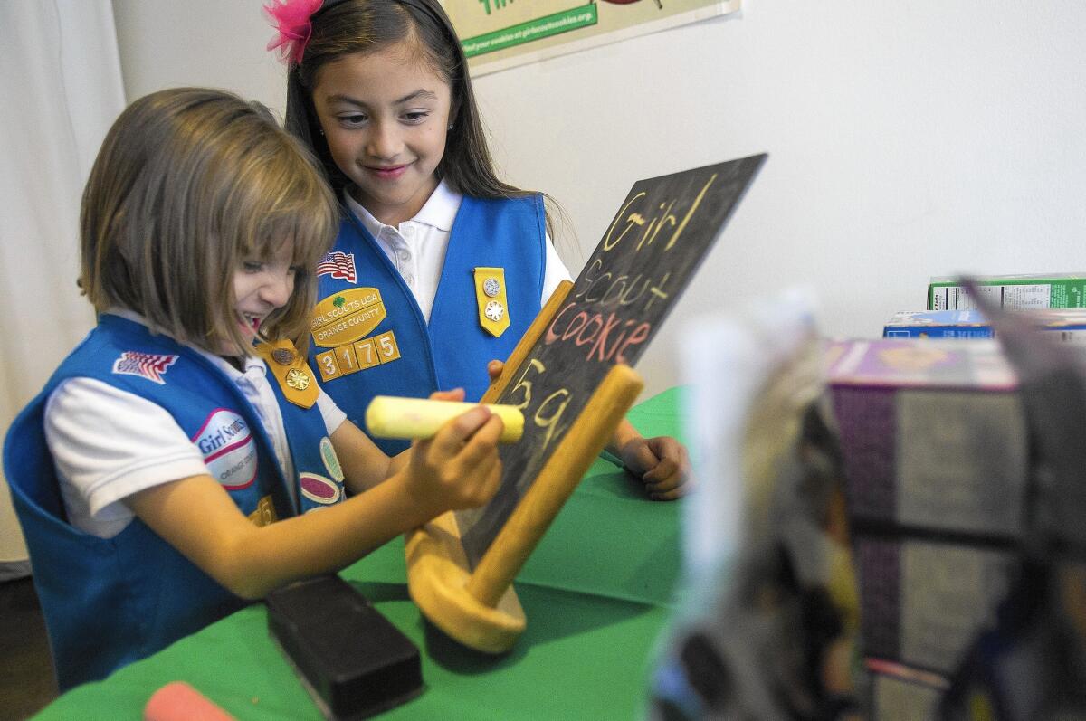 Amelia Zuniga, 6, left, and Christina Rodriguez, 6, with Daisy Troop 3175 make a sign in preparation of selling Girl Scout cookies at The OC Mix on Wednesday.