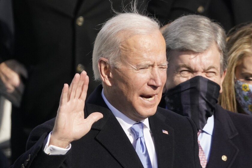 Joe Biden raises his hand while taking the oath of office.