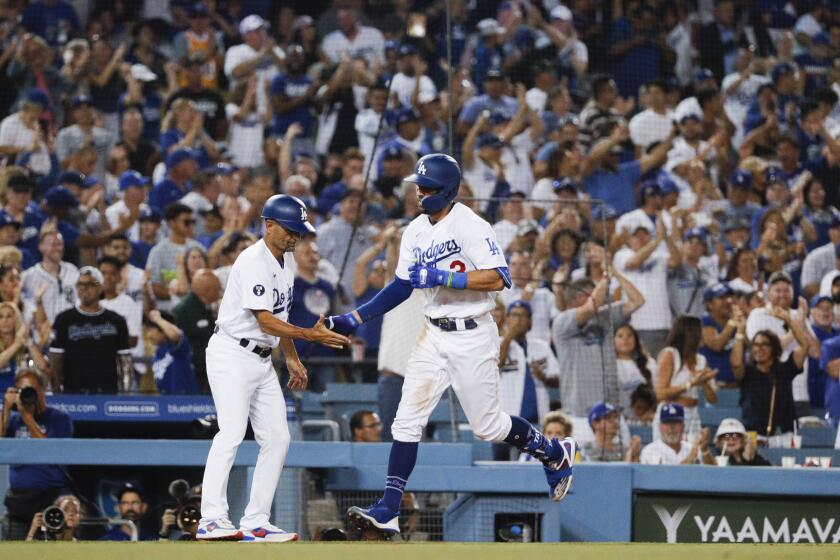 Los Angeles, CA - August 10: Los Angeles Dodgers third base coach Dino Ebel, left, congratulates Chris Taylor after Taylor's go-ahead solo home run during the sixth inning against the Minnesota Twins at Dodger Stadium on Wednesday, Aug. 10, 2022 in Los Angeles, CA.(Gina Ferazzi / Los Angeles Times)