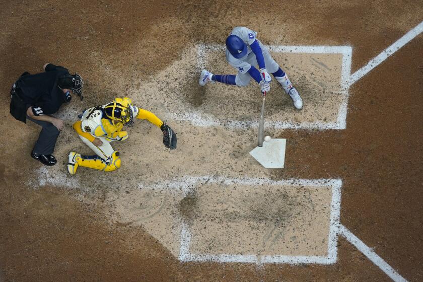 Los Angeles Dodgers' Mookie Betts, right, hits an RBI single during the seventh inning of a baseball game against the Milwaukee Brewers, Monday, Aug. 12, 2024, in Milwaukee. (AP Photo/Aaron Gash)