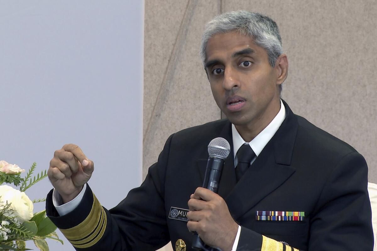 Surgeon General Vivek Murthy holds a microphone as he speaks.