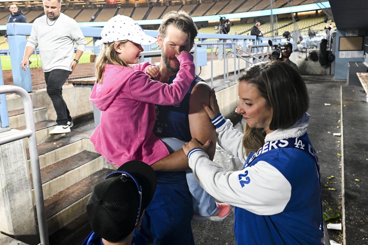 Dodgers starting pitcher Clayton Kershaw meets with his wife, Ellen, and daughter, Cali Ann, in the dugout after a game.