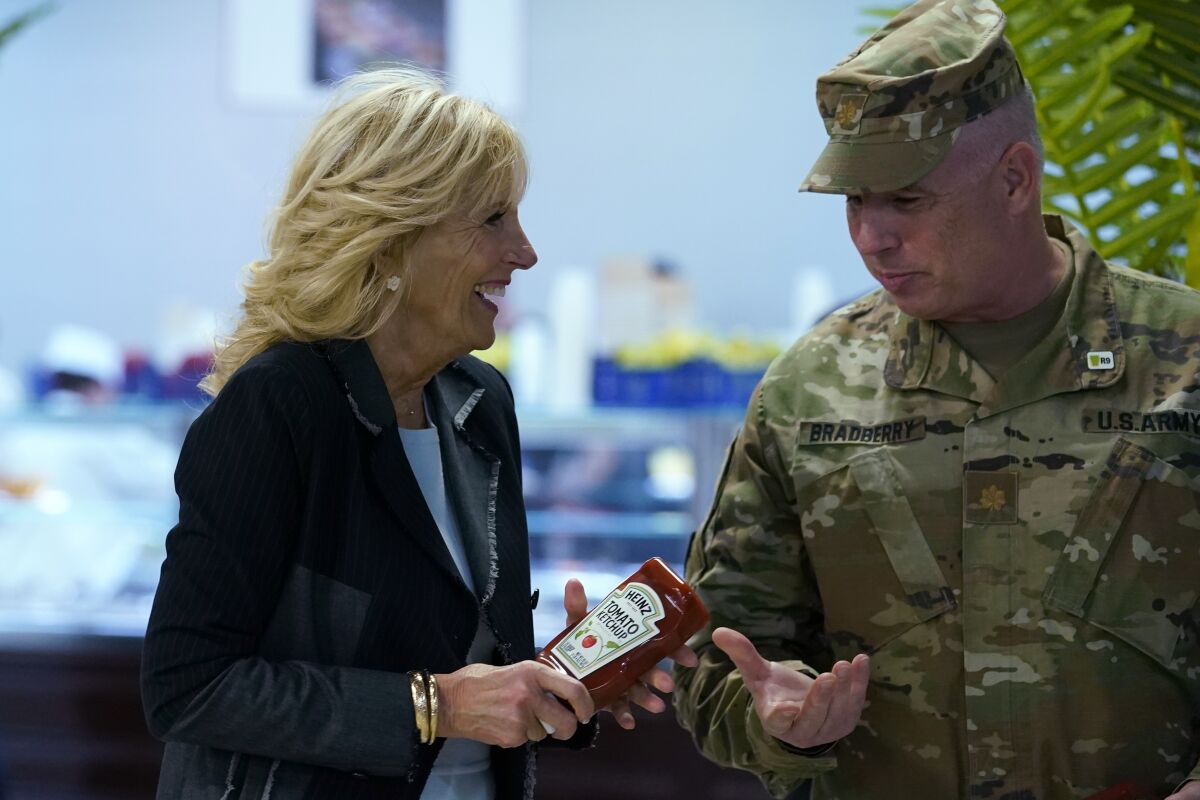 First lady Jill Biden, left, gives bottles of ketchup to Major Shawn Bradberry, U.S. Army Deputy Host Nation Advisor for Romania, right, during her visit to the Mihail Kogalniceanu Air Base in Romania, Friday, May 6, 2022. The base was out of ketchup. Biden also served meals to and visit with some of the U.S. troops assigned to the base during her visit. (AP Photo/Susan Walsh, Pool)