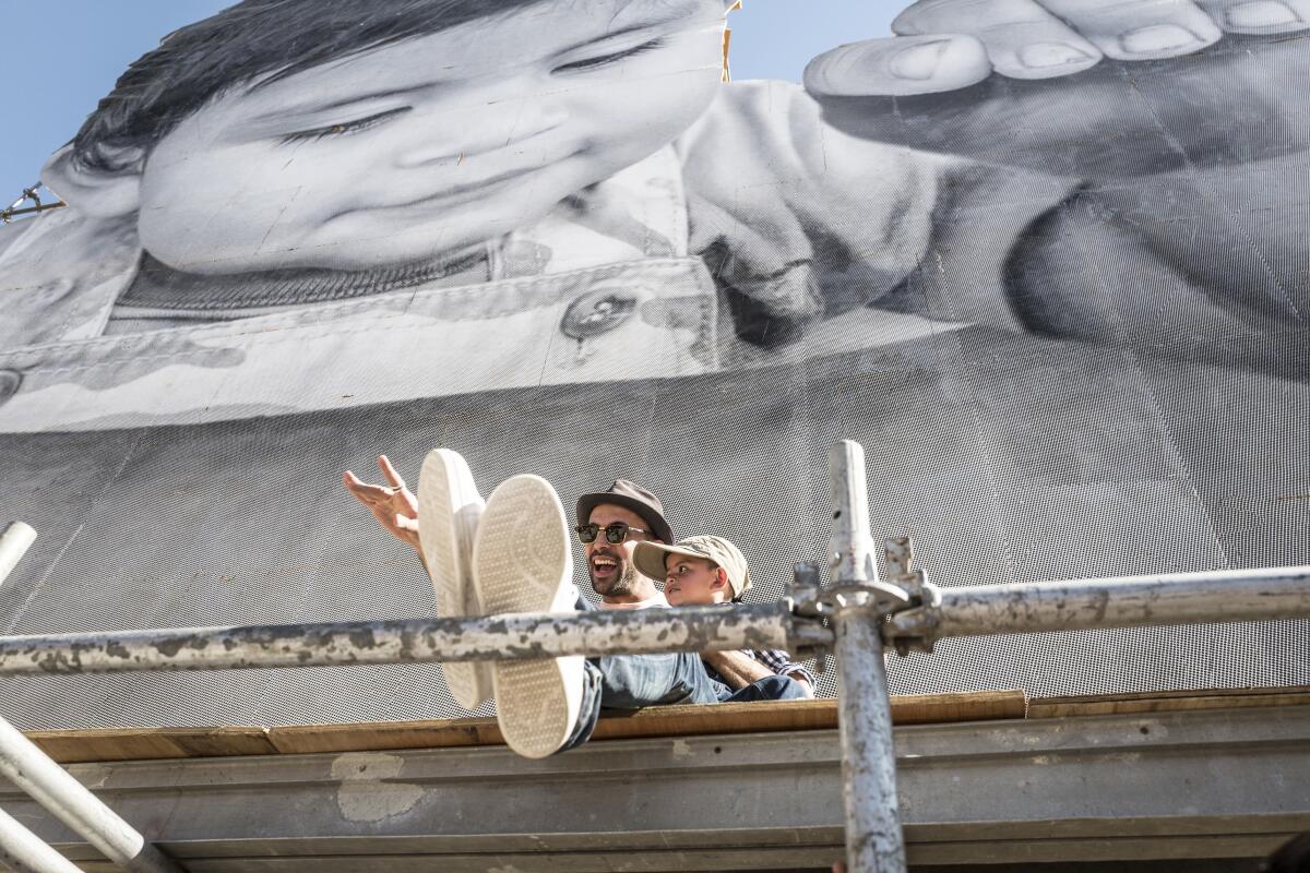 A man and a child sit on scaffolding in the documentary "Paper & Glue."