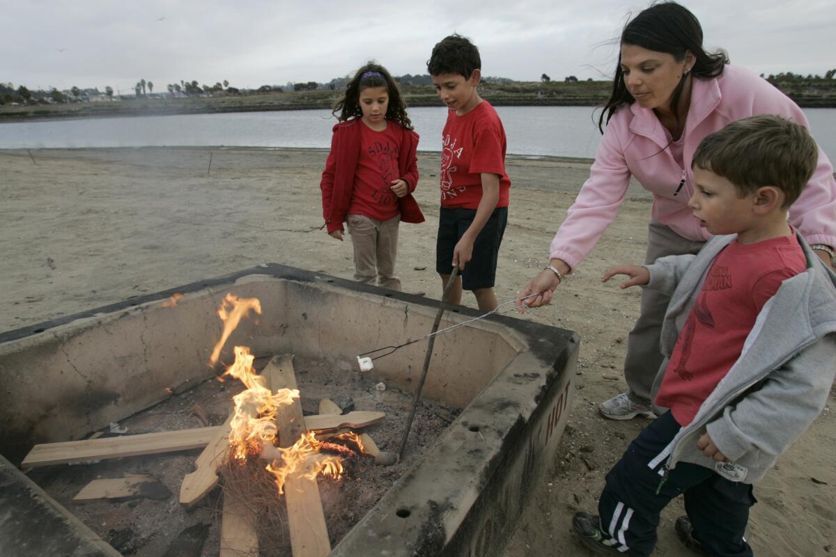 A family roasts marshmallows in a fire pit on Fiesta Island.