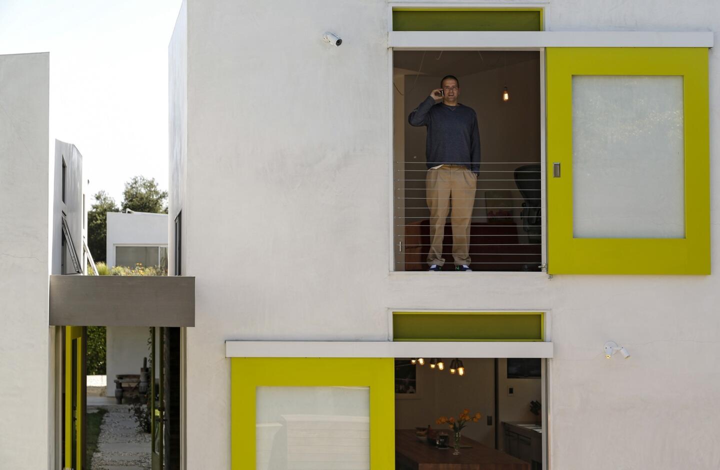 Jamie Sobieski stands at a second-floor doorway whose sliding track creates an arresting design as seen from the second floor of another building on the property.
