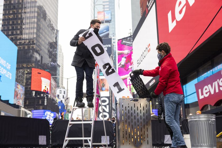 Times Square Alliance burn a 2021 banner in Times Square, Tuesday, Dec. 28, 2021, in New York.