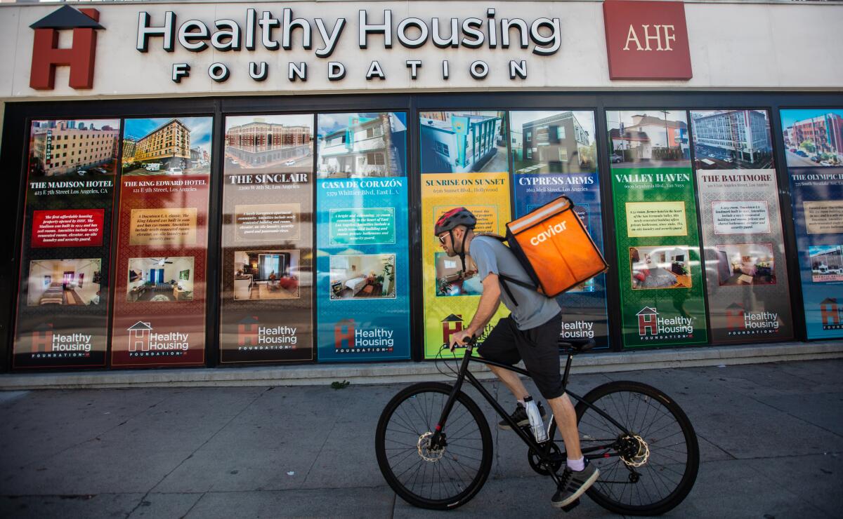 A bicyclist goes by a building with the words "Healthy Housing Foundation" on it.