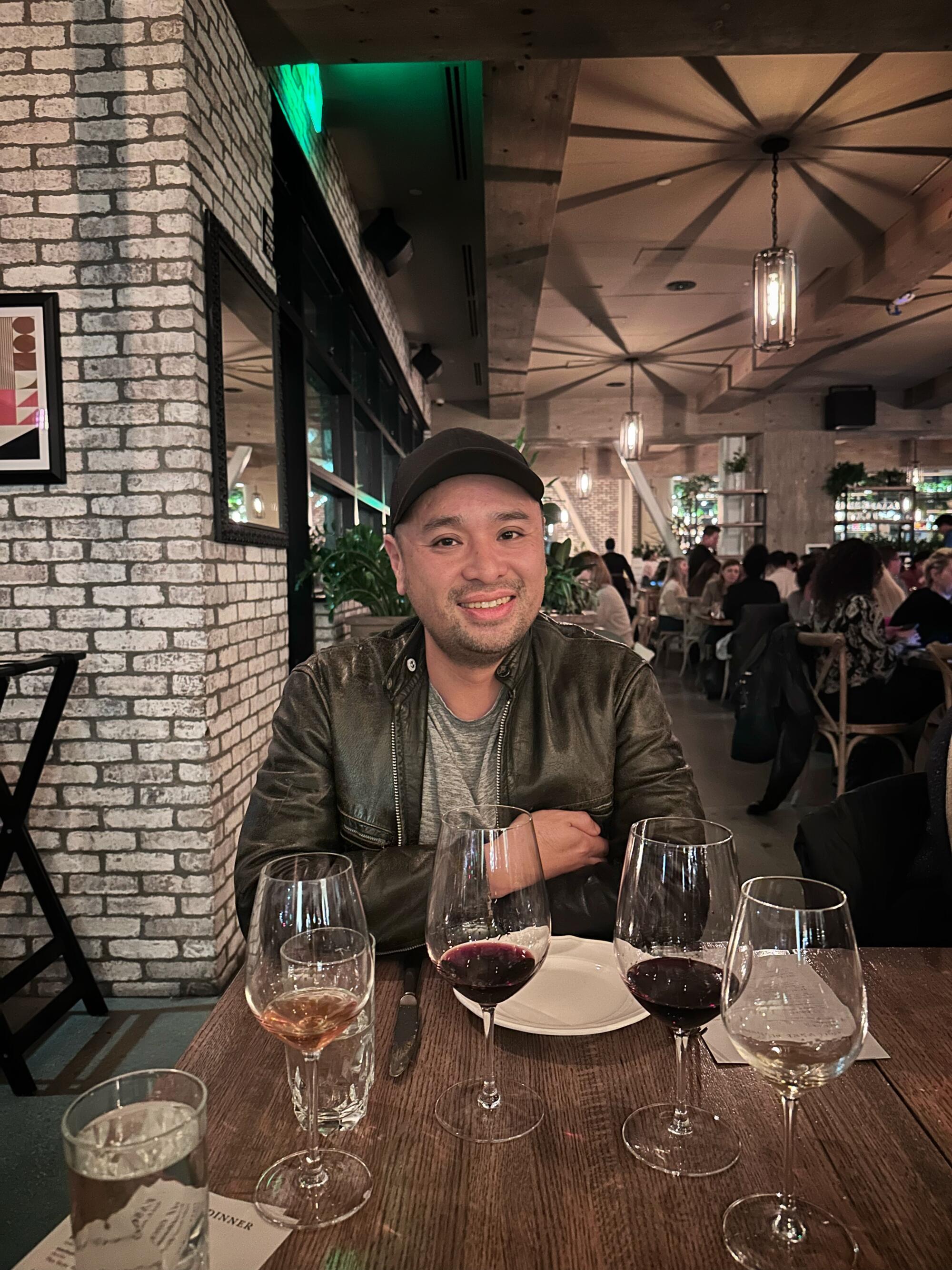 Shawn Pham smiles at a table full of wine glasses.