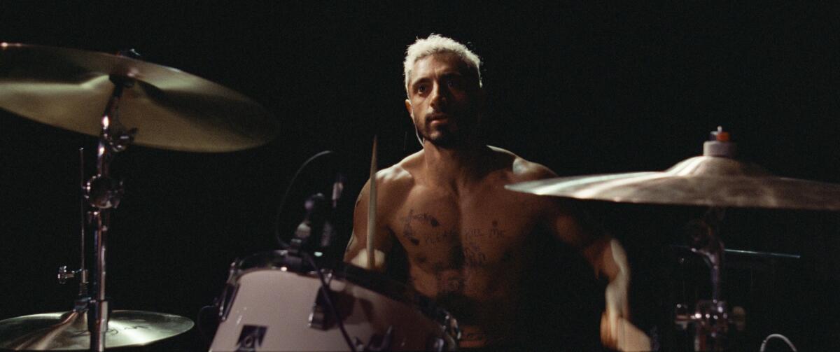 a shirtless man drumming on a drum set