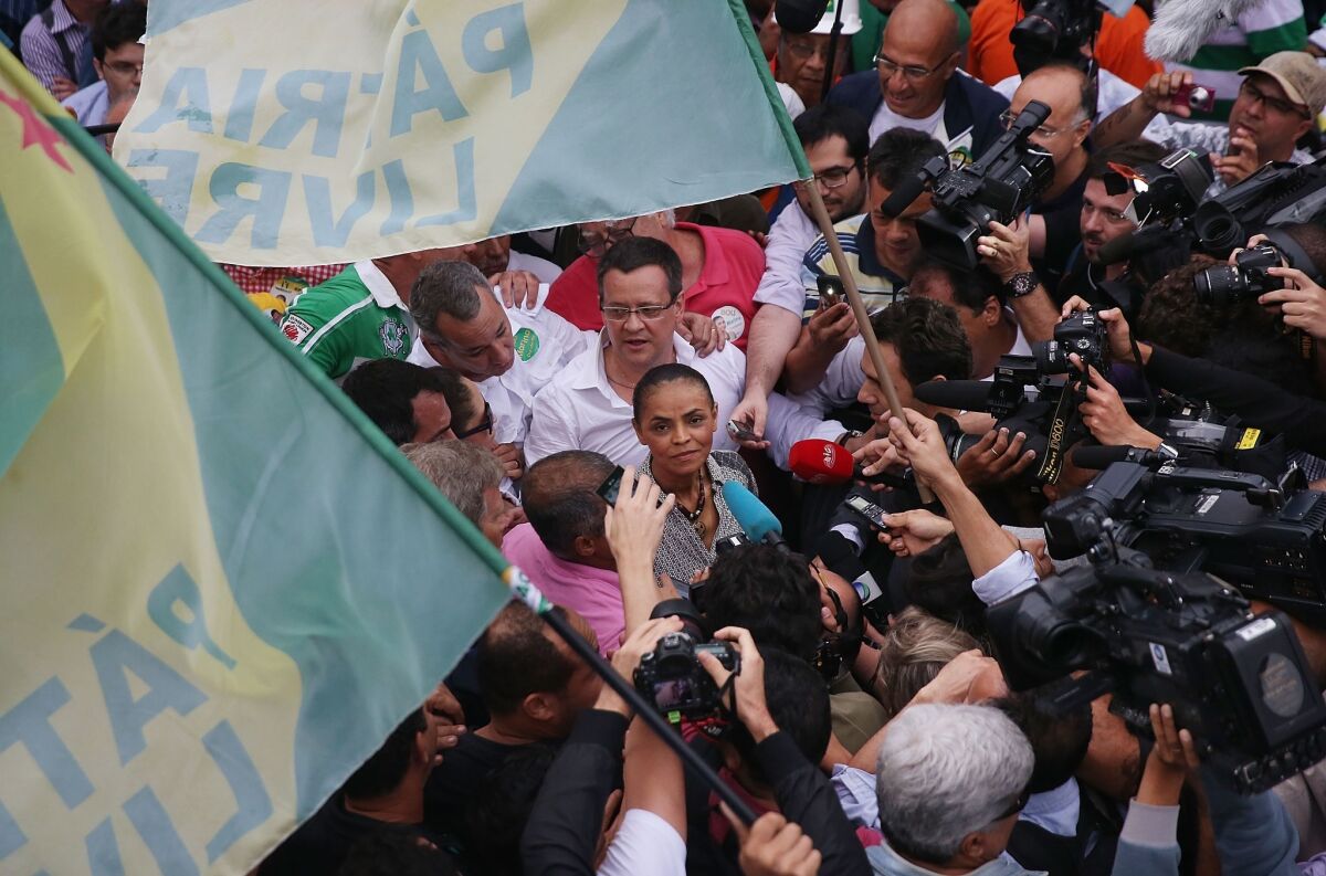 Marina Silva, surrounded by journalists, greets a supporter in the Rocinha favela in Rio de Janeiro Aug. 30, 2014.