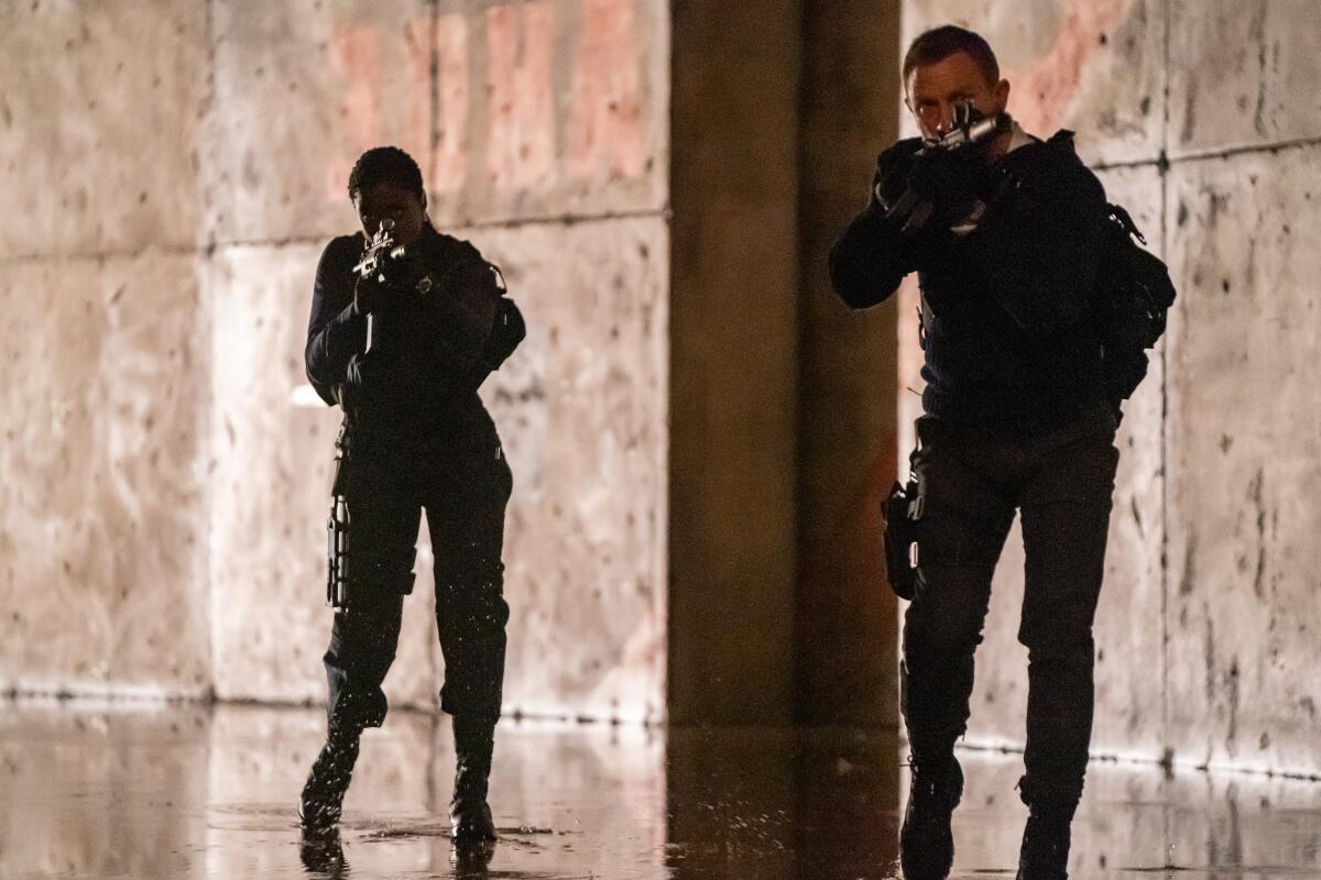Nomi (Lashana Lynch) and James Bond (Daniel Craig) holding guns.