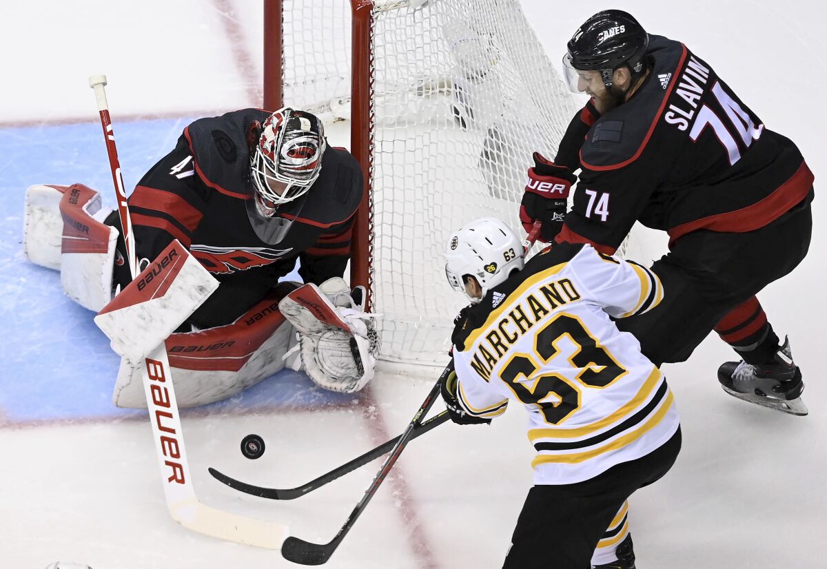 Carolina Hurricanes goaltender James Reimer (47) makes a save on a shot from Boston Bruins left wing Brad Marchand (63) as Hurricanes defenseman Jaccob Slavin (74) looks on during first-period NHL Eastern Conference Stanley Cup playoff hockey action in Toronto, Monday, Aug. 17, 2020. (Nathan Denette/The Canadian Press via AP)