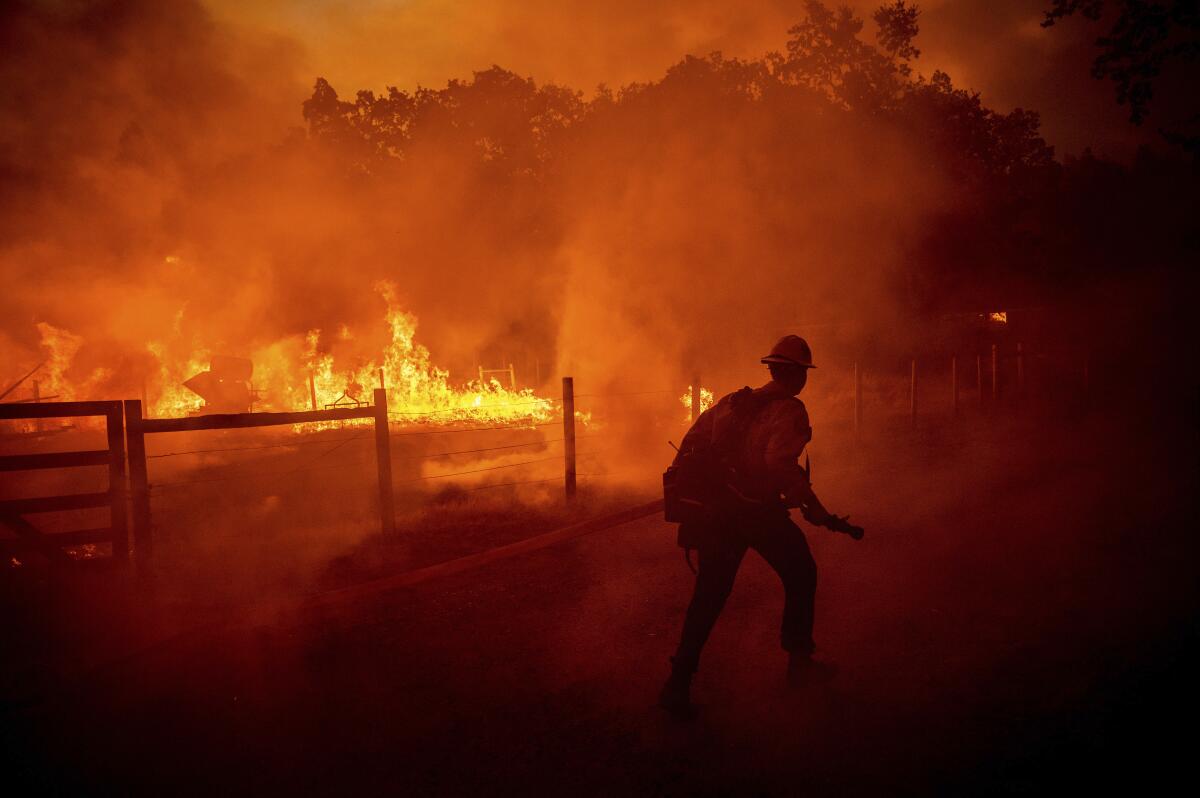 Un bombero intenta apagar las llamas de un incendio forestal, el 22 de julio de 2022, en Darrah Road,